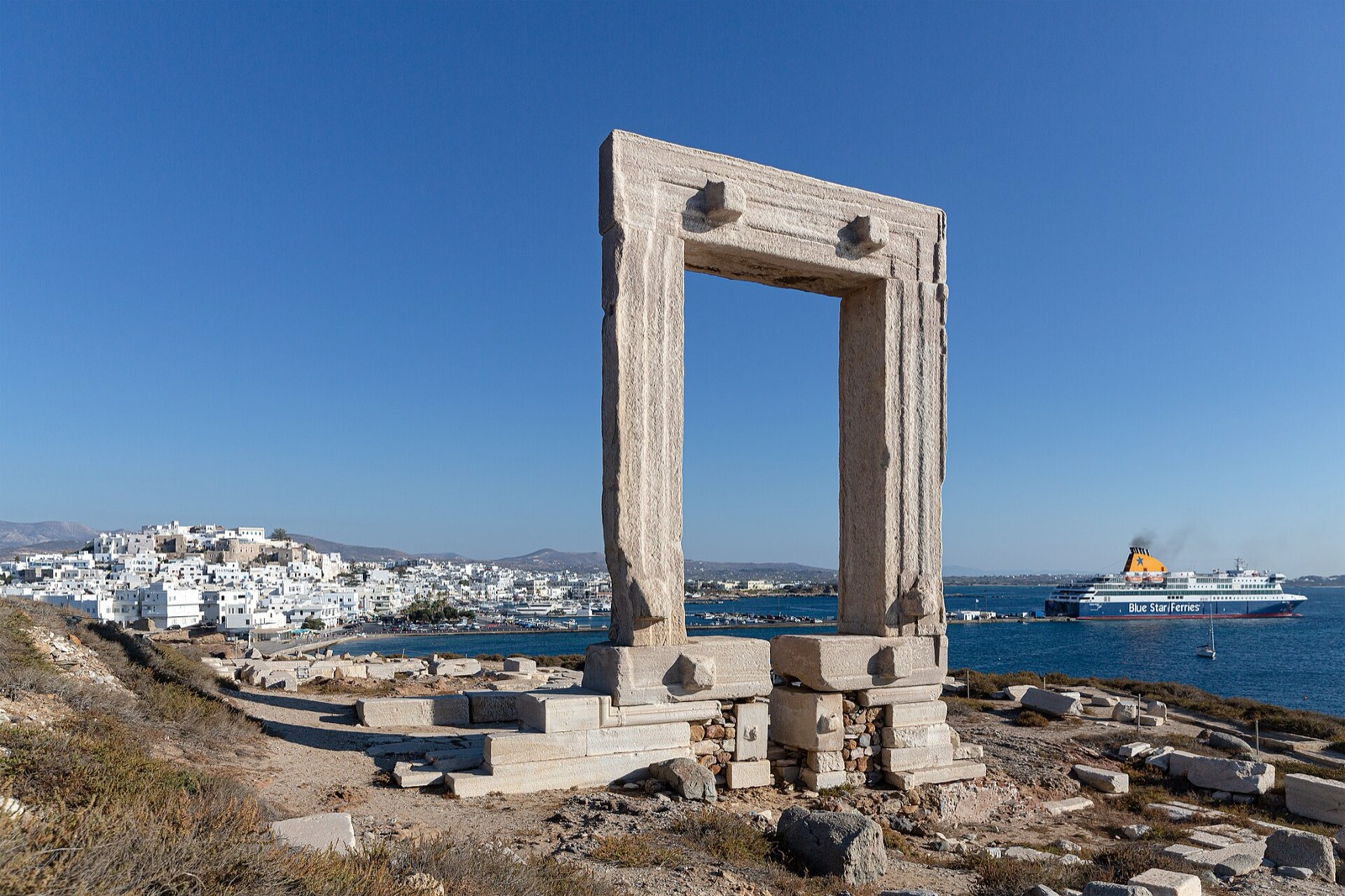 The Portara gateway on Naxos with a ferry in the channel
