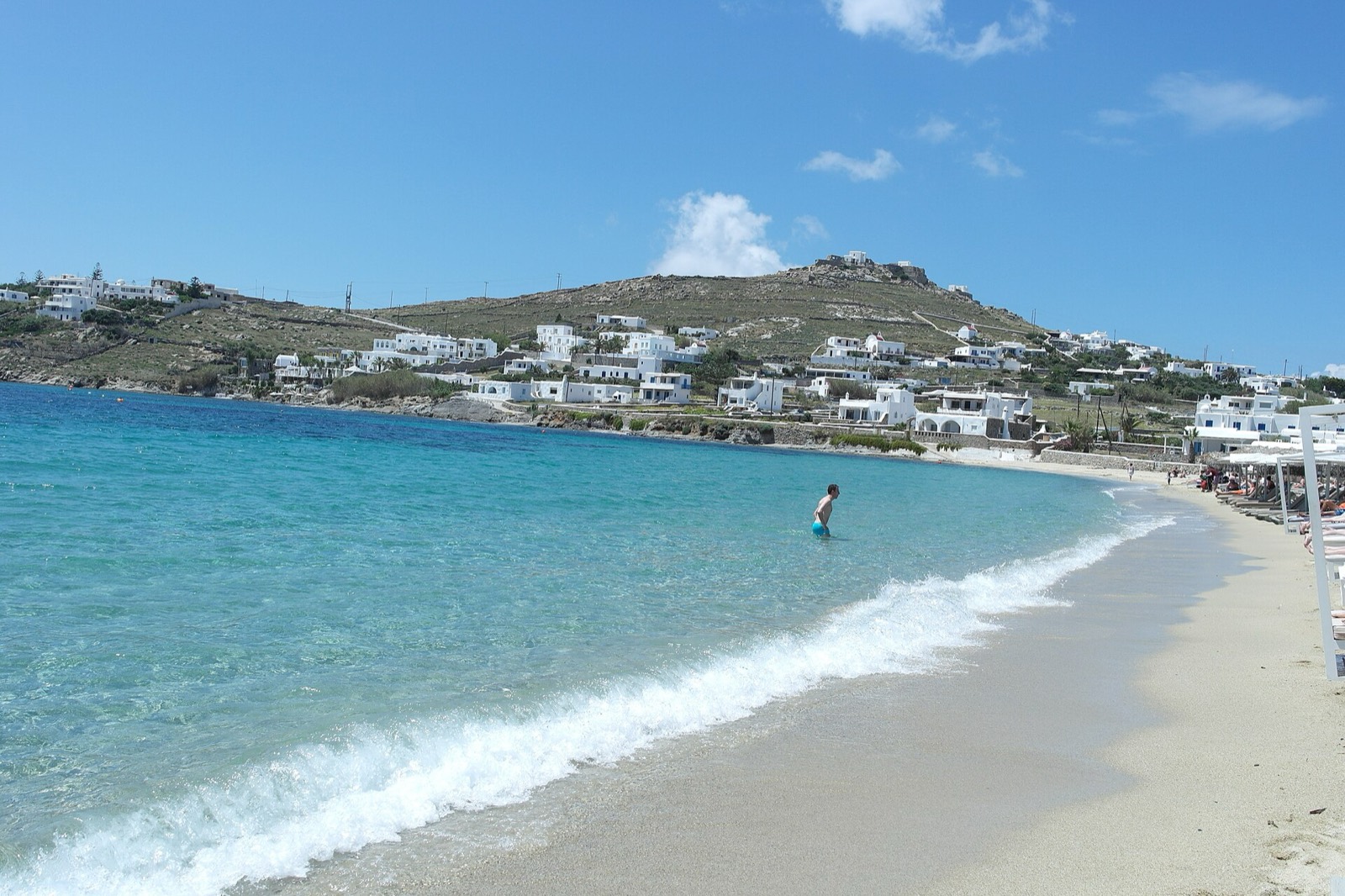 Calm water at Ornos beach with the village behind